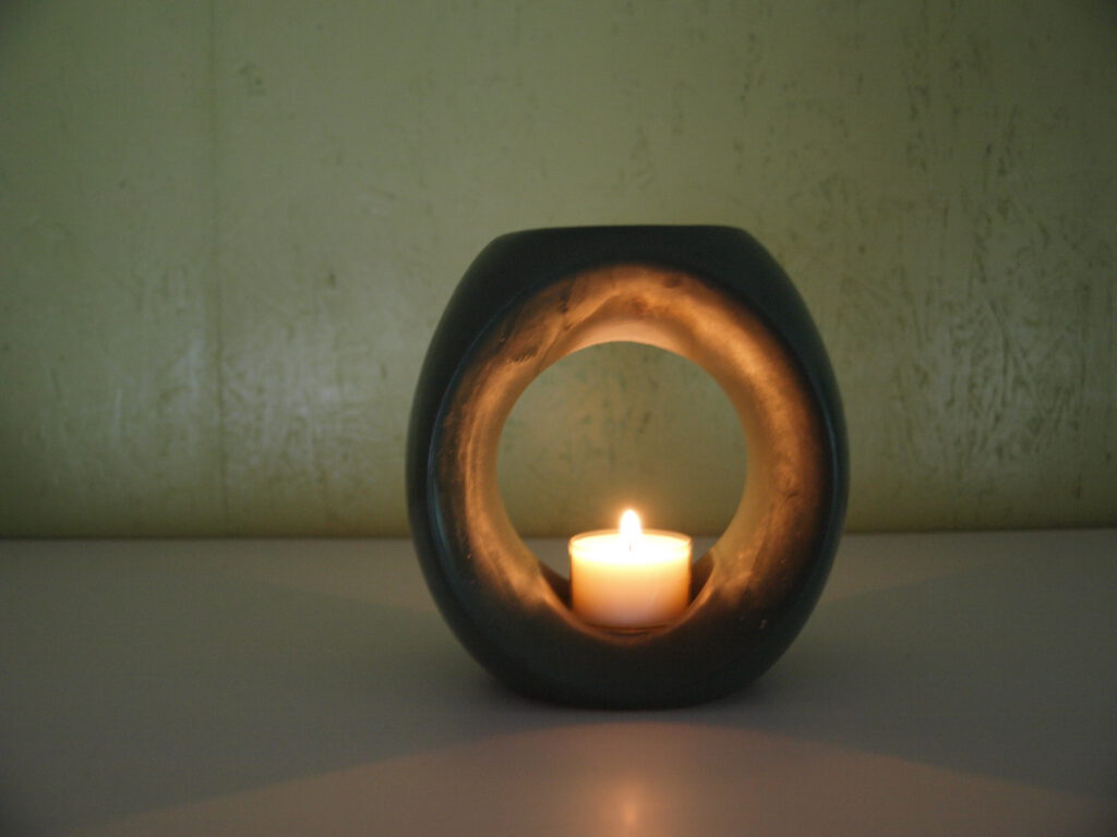 Kerze in der Duftlampfe, die im oberen Bereich als Schale gearbeitet ist und die ätherischen Tropfen aufnimmt.