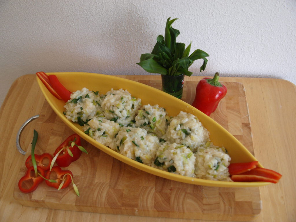 Finales weiß-grünes Bärlauch Risotto in konstrastierender Garnitur aus roten Paprikastücken und grünen Bärlauchblättern.