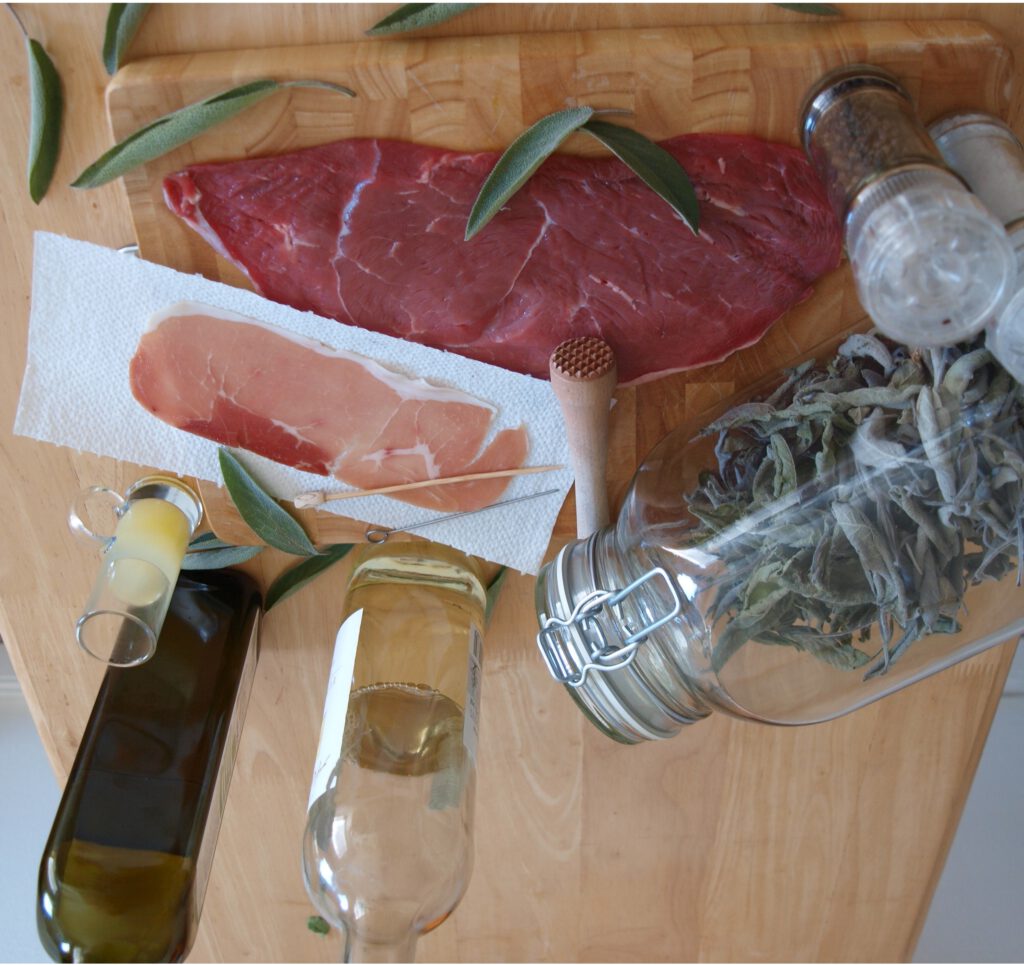 Zutaten für die traditionelle Kalbsschnitzelzubereitung inklusive Salbei, Schinken, Weißwein, Öl